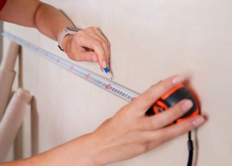 image of a hand holding a pencil, holding a ruler to measure the size of the photo space