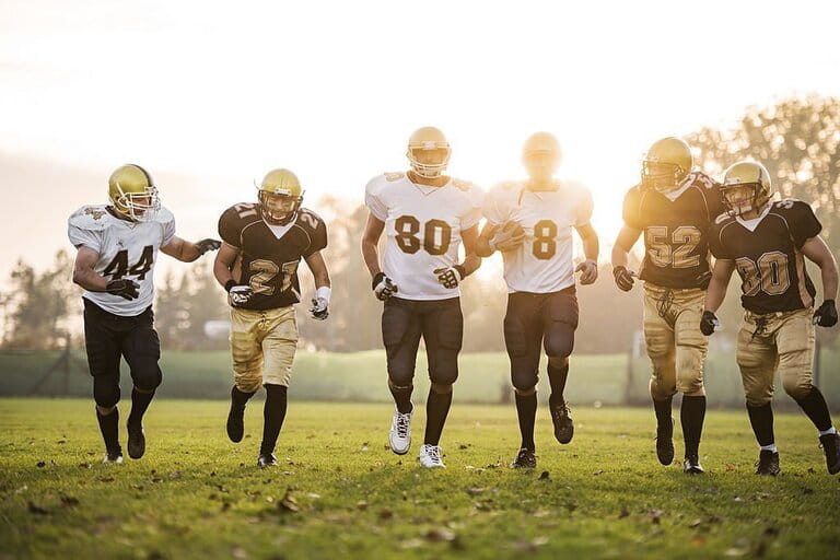 Football player running on the stadium in bright sunshine