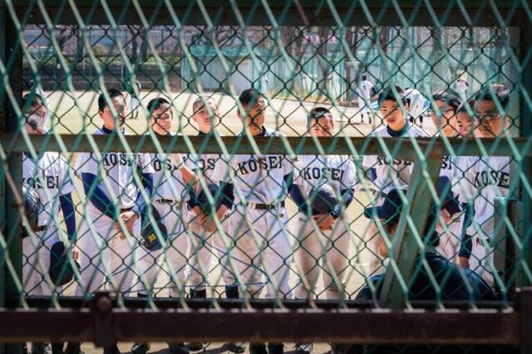A young baseball team receive instructions from the coach at Taito Riverside Baseball Field along the Sumida River, Tokyo