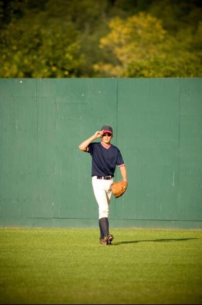 Young outfielder adjusting his sunglasses on baseball field Young outfielder adjusting his sunglasses on baseball field