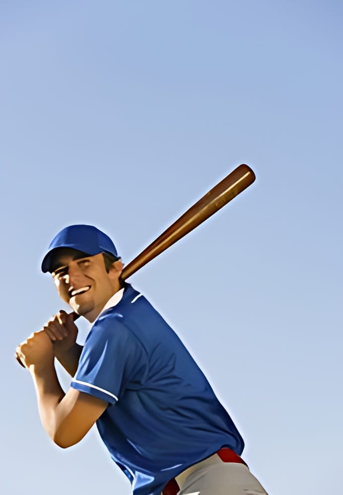 Low angle view of a happy baseball player swinging baseball bat against clear blue sky Low angle view of a happy baseball player swinging baseball bat against clear blue sky