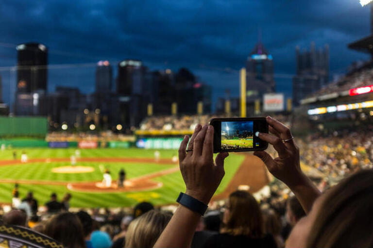 Hands of woman photographing baseball game with cell phone Hands of woman photographing baseball game with cell phone