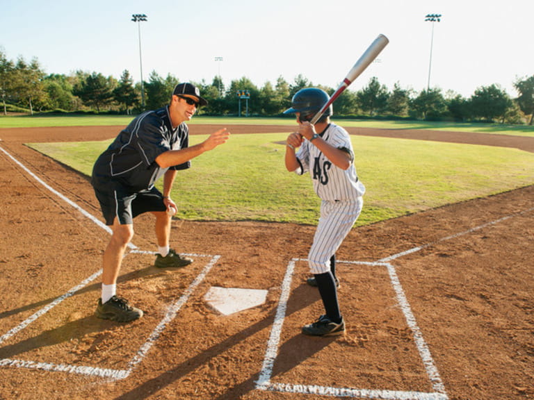 Baseball coach and boy (10-11) standing on baseball diamond
