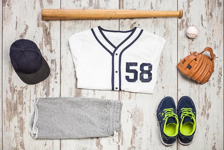 Bunch of sportswear and baseball equipment on a white hardwood floor