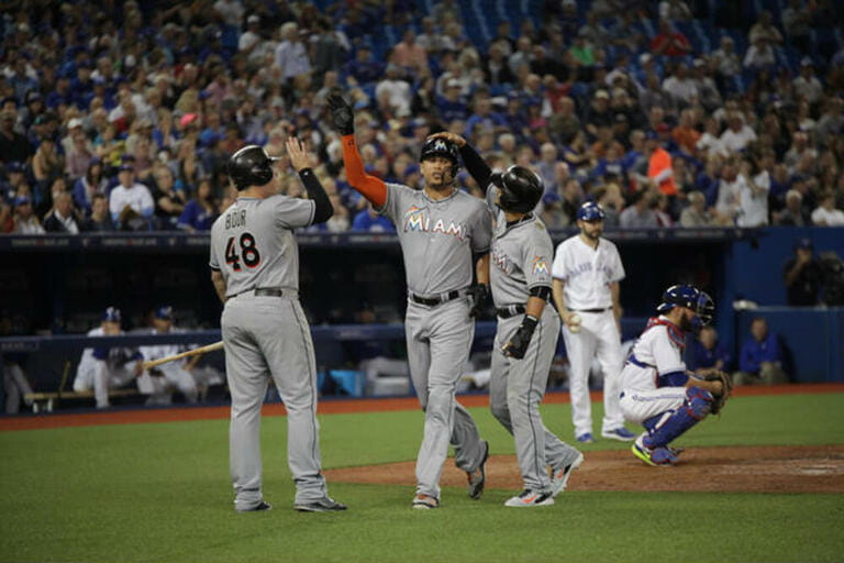 Miami Marlins players congratulate each other on scoring a run