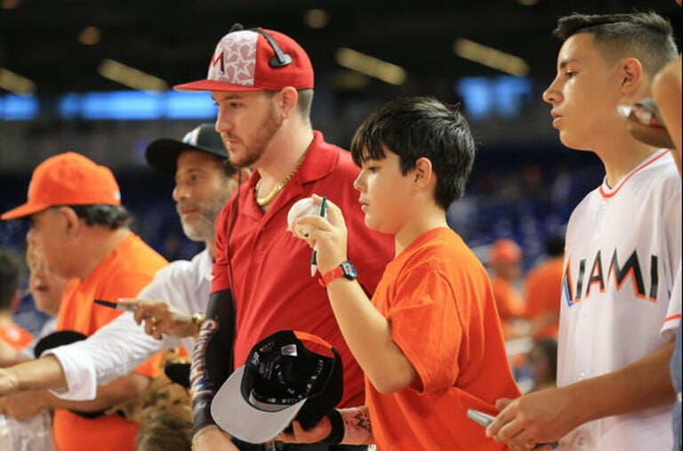 Miami Marlins fans ask for autographs as some of the team players arrive to the dugout before a MLB game between the New York Mets and the Miami Marlins at the Marlins Park, in Miami, Florida. Miami Marlins fans ask for autographs as some of the team players arrive to the dugout before a MLB game between the New York Mets and the Miami Marlins at the Marlins Park, in Miami, Florida.