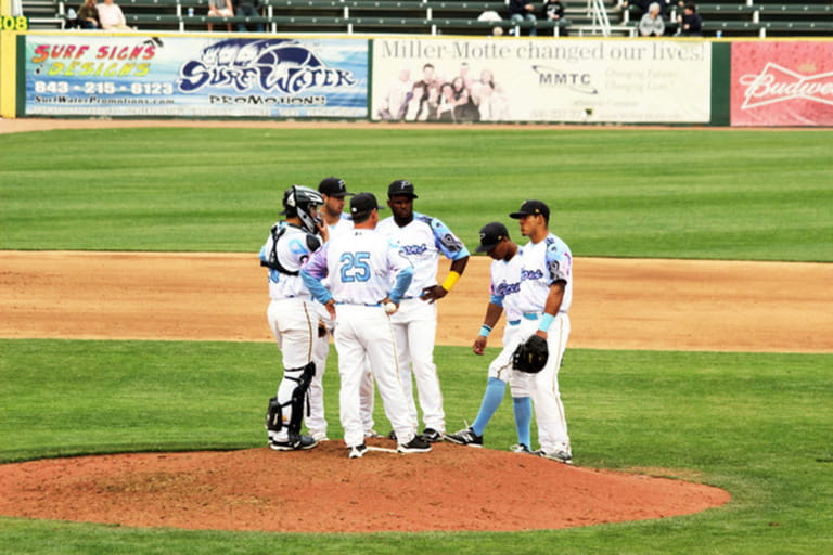 A baseball team converges on the pitchers mound to discuss strategy.