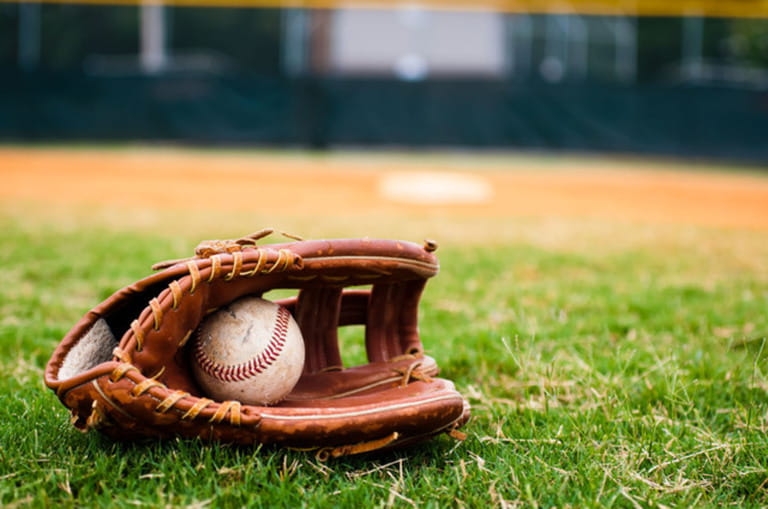 Baseball in glove on field with base and outfield in background. Baseball in glove on field with base and outfield in background.